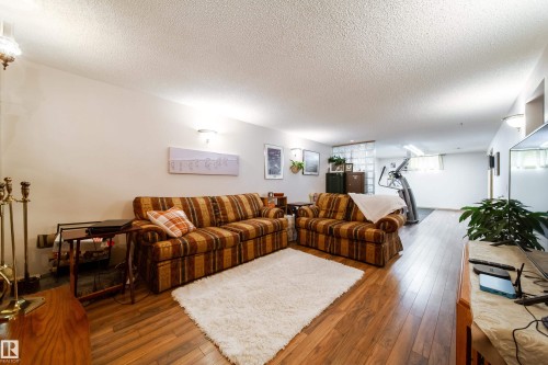 Spacious finished lower level with wood-finish flooring, recessed wall lighting, and a textured ceiling - 8932 154 Street, Edmonton, AB - Indoor Photo Showing Living Room