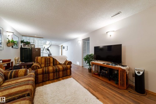 Spacious room featuring wood-finish flooring, light-toned walls, and sconce lighting fixtures - 8932 154 Street, Edmonton, AB - Indoor Photo Showing Living Room