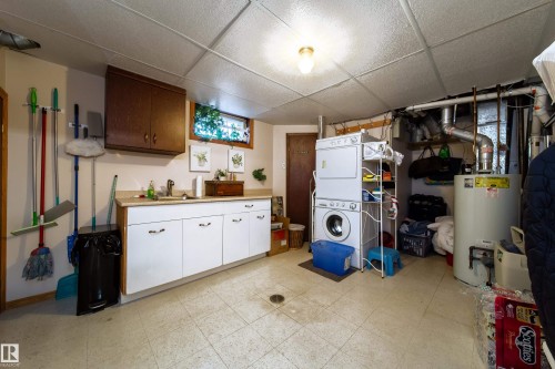 Laundry area featuring a drop ceiling, a utility sink with white cabinetry, and an upper wood-finish cabinet - 8932 154 Street, Edmonton, AB - Indoor