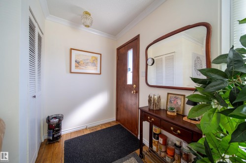 Entryway featuring wood-finish flooring, a solid wood door with frosted glass insert, and a built-in louvered closet - 8932 154 Street, Edmonton, AB - Indoor Photo Showing Other Room