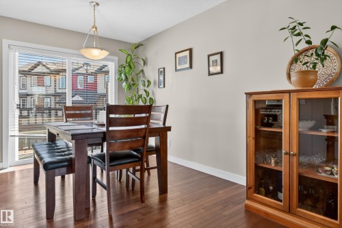 Dining area featuring a sliding glass door, overhead semi-flush mount lighting, and wood-finish flooring - 1786 Cunningham Way Sw, Edmonton, AB - Indoor Photo Showing Dining Room