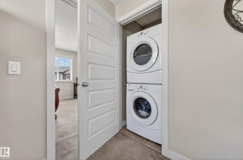 Dedicated laundry closet featuring a white stackable washer and dryer - 1786 Cunningham Way Sw, Edmonton, AB - Indoor Photo Showing Laundry Room