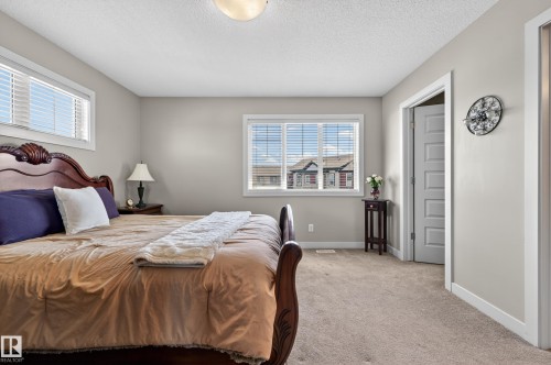 Carpeted bedroom featuring multiple windows with blinds, a five-panel interior door, and neutral wall paint - 1786 Cunningham Way Sw, Edmonton, AB - Indoor Photo Showing Bedroom