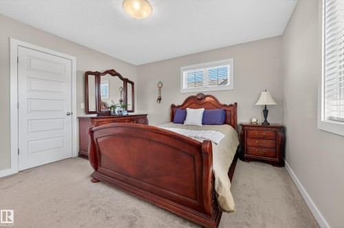 Carpeted room featuring a ceiling-mounted light fixture, multiple windows with blinds, and light-colored wall paint - 1786 Cunningham Way Sw, Edmonton, AB - Indoor Photo Showing Bedroom
