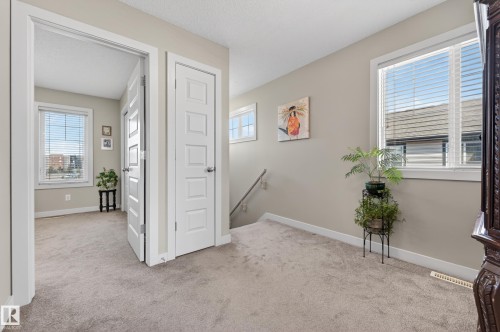 Spacious interior hallway featuring neutral wall paint, white trim, and light-toned carpet flooring - 1786 Cunningham Way Sw, Edmonton, AB - Indoor Photo Showing Other Room