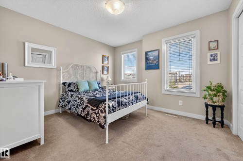 Carpeted room featuring two windows with horizontal blinds, neutral-toned walls, and white trim - 1786 Cunningham Way Sw, Edmonton, AB - Indoor Photo Showing Bedroom