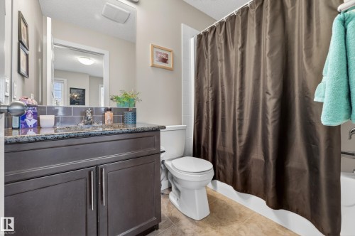 Bathroom featuring a dark wood vanity with a speckled countertop, undermount sink, and subway tile backsplash - 1786 Cunningham Way Sw, Edmonton, AB - Indoor Photo Showing Bathroom