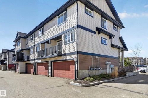 Multi-level townhome exterior featuring light-colored siding with dark trim accents - 1786 Cunningham Way Sw, Edmonton, AB - Outdoor