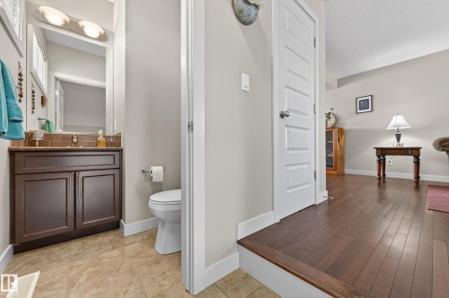 Powder room featuring a dark wood-finish vanity with a light brown countertop, a tiled backsplash, and an overhead vanity light fixture - 1786 Cunningham Way Sw, Edmonton, AB - Indoor Photo Showing Bathroom