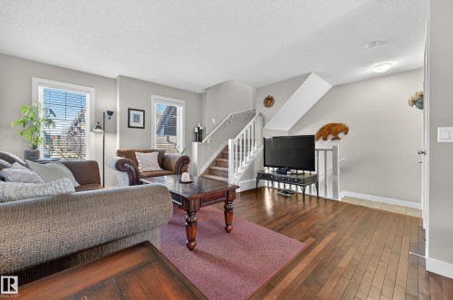 Spacious living area featuring wood-finish flooring, light grey walls, and white trim - 1786 Cunningham Way Sw, Edmonton, AB - Indoor Photo Showing Living Room