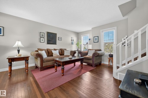 Bright living area featuring wood-finish flooring, light gray wall paint, white trim, and multiple windows - 1786 Cunningham Way Sw, Edmonton, AB - Indoor Photo Showing Living Room