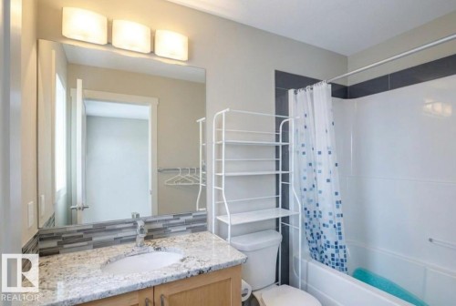 Bathroom featuring a granite-style countertop, undermount sink, and a tiled backsplash - 16619 14 Avenue, Edmonton, AB - Indoor Photo Showing Bathroom