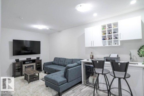 Entertainment area featuring wood-finish flooring, a built-in wet bar with a stainless steel sink, under-counter beverage cooler, and overhead cabinetry with integrated wine storage - 16619 14 Avenue, Edmonton, AB - Indoor