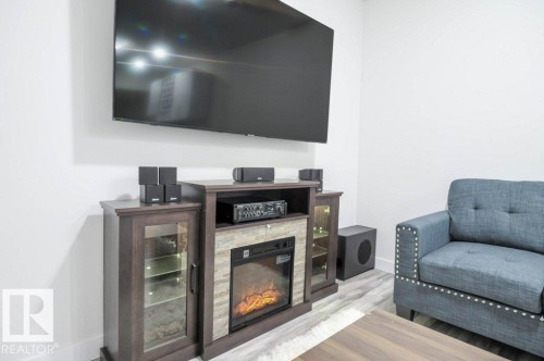 Media console with an integrated electric fireplace and stone surround - 16619 14 Avenue, Edmonton, AB - Indoor With Fireplace
