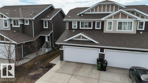 Contemporary townhome exterior featuring multi-toned siding, stone accents, and a dual garage - 16619 14 Avenue, Edmonton, AB - Outdoor With Facade