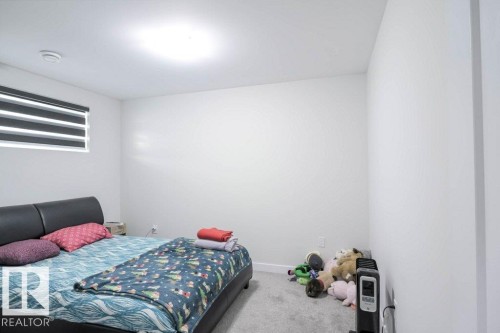 Bedroom featuring light gray carpeting, a window with horizontal blinds, and a built-in overhead light fixture - 16619 14 Avenue, Edmonton, AB - Indoor Photo Showing Bedroom