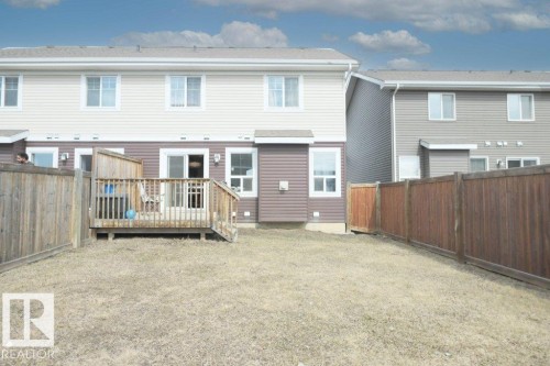 Private fenced backyard featuring a wooden deck, sliding glass patio door, and vinyl siding exterior - 16619 14 Avenue, Edmonton, AB - Outdoor With Exterior