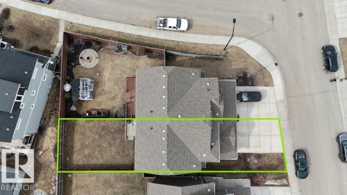 Aerial view highlighting the property boundaries, a multi-gabled roofline, concrete driveway, and a rear yard with a fire pit area - 16619 14 Avenue, Edmonton, AB - 