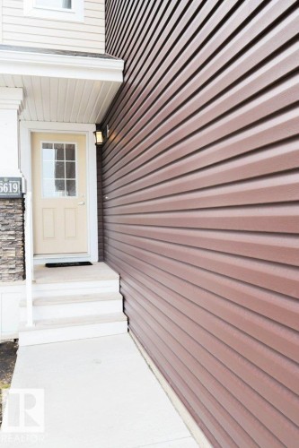 Brown horizontal siding exterior with a light-colored entry door featuring glass panels - 16619 14 Avenue, Edmonton, AB - Outdoor With Exterior