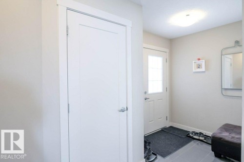 Entryway featuring a white paneled door, a white front door with multiple glass panes, light gray wall paint, and gray square floor tiles - 16619 14 Avenue, Edmonton, AB - Indoor Photo Showing Other Room