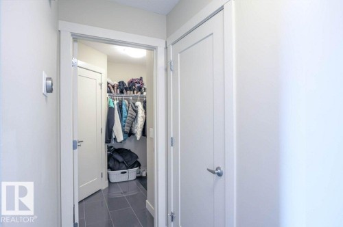 Entryway closet with dark tile flooring, white walls, and a built-in shelving system - 16619 14 Avenue, Edmonton, AB - Indoor