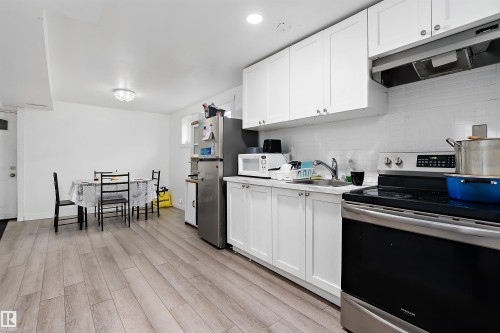 Bright kitchen featuring white shaker cabinetry, stainless steel range, white subway tile backsplash, and light wood-finish flooring - 11919 96 Street, Edmonton, AB - Indoor Photo Showing Kitchen