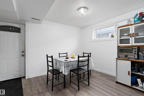 Bright dining area featuring wood-finish flooring and a crystal flush mount ceiling light - 11919 96 Street, Edmonton, AB - Indoor Photo Showing Dining Room