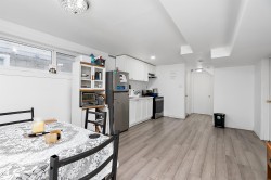 Open-concept kitchen and dining area featuring white cabinetry, stainless steel appliances, and wood-finish flooring - 