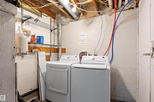 Dedicated laundry area featuring a white washing machine and dryer, exposed ceiling joists, and visible utility lines - 11919 96 Street, Edmonton, AB - Indoor Photo Showing Laundry Room