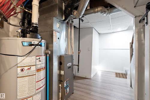 Mechanical room featuring a water heater, furnace, exposed ductwork, and white walls - 11919 96 Street, Edmonton, AB - Indoor Photo Showing Basement