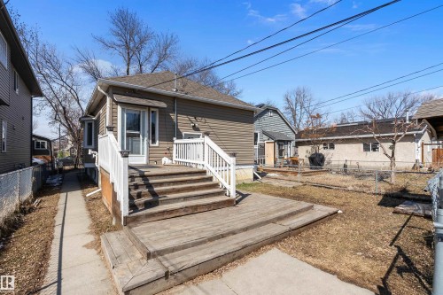 Rear exterior featuring a multi-level wood deck with white railings, a brown siding facade, a bay window, and a gabled roof - 11919 96 Street, Edmonton, AB - Outdoor
