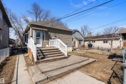 Rear exterior featuring a multi-level wood deck with white railings, a brown siding facade, a bay window, and a gabled roof - 