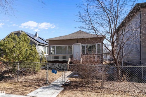 Single-story property with brown siding, a front porch with white railing, and a chain-link fence - 11919 96 Street, Edmonton, AB - Outdoor With Deck Patio Veranda