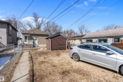 Rear exterior featuring a brown siding structure, a detached brown shed, and a chain-link fence - 