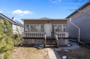 Front façade featuring brown siding, multiple windows, a white entry door, and a front porch with white railings and lattice skirting - 11919 96 Street, Edmonton, AB  - Outdoor With Deck Patio Veranda 