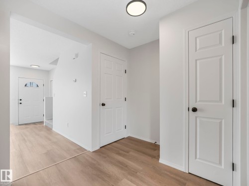 The property features light wood flooring, white paneled doors with black hardware, and overhead flush-mount lighting fixtures - 14 15128 22 Street, Edmonton, AB - Indoor Photo Showing Other Room