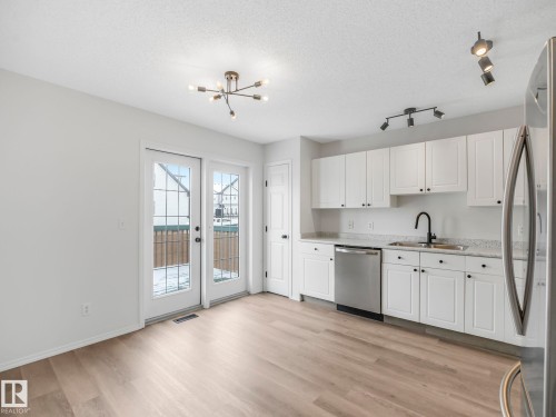 The kitchen features white cabinetry, stainless steel appliances, and light-toned flooring - 14 15128 22 Street, Edmonton, AB - Indoor Photo Showing Kitchen