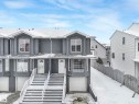 Townhome with a two-car garage and a paved driveway, featuring multiple windows and a front door with an arched window detail - 14 15128 22 Street, Edmonton, AB  - Outdoor With Facade 