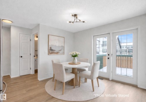 This dining area features light-toned flooring, white walls, and a contemporary light fixture. Photo Virtually Staged. - 14 15128 22 Street, Edmonton, AB - Indoor Photo Showing Dining Room