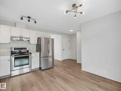 The kitchen features white cabinetry, stainless steel appliances, and light-colored countertops - 14 15128 22 Street, Edmonton, AB - Indoor Photo Showing Kitchen