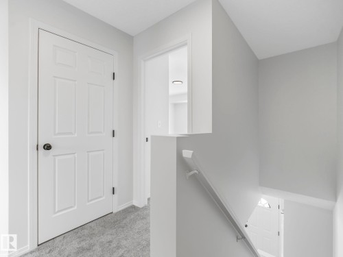 The property features a hallway with light gray carpeting and white paneled doors - 14 15128 22 Street, Edmonton, AB - Indoor Photo Showing Other Room