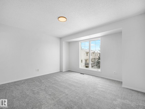 This room features light grey carpeting, white walls, and a large window providing ample natural light - 14 15128 22 Street, Edmonton, AB - Indoor Photo Showing Other Room