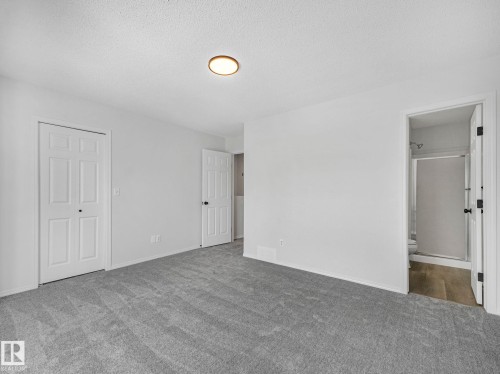 Spacious room featuring light grey carpet, white walls, and a modern ceiling light fixture - 14 15128 22 Street, Edmonton, AB - Indoor Photo Showing Other Room