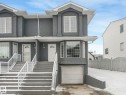 The property features a private garage, exterior stairs with white railings, and bay windows - 14 15128 22 Street, Edmonton, AB  - Outdoor With Facade 