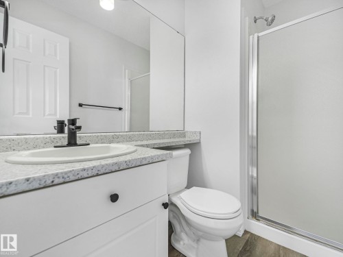Bathroom featuring a vanity with a white sink, dark-toned faucet, and a spacious mirror - 14 15128 22 Street, Edmonton, AB - Indoor Photo Showing Bathroom