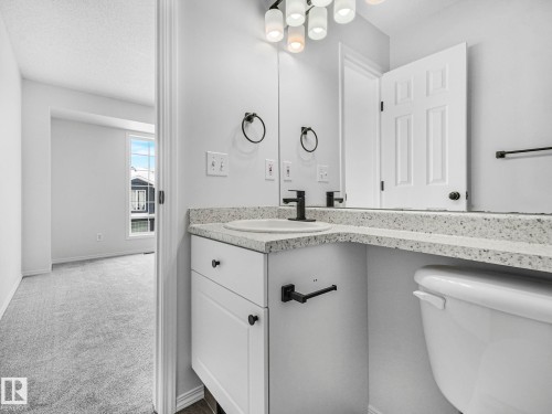Bathroom featuring a white vanity with a light-colored countertop, a sink with a dark faucet, and a wall mirror - 14 15128 22 Street, Edmonton, AB - Indoor Photo Showing Bathroom