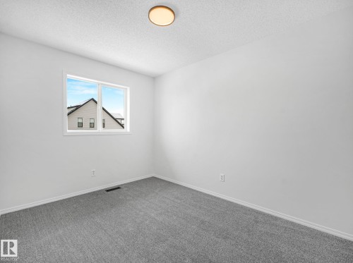 The room features light gray carpeting, white walls, and a window providing natural light - 14 15128 22 Street, Edmonton, AB - Indoor Photo Showing Other Room