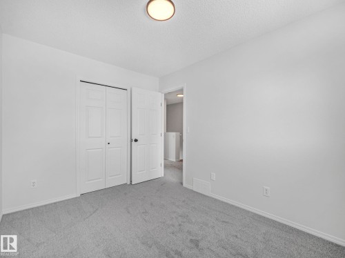 This room features neutral-toned carpeting, light-colored walls, and a ceiling light fixture - 14 15128 22 Street, Edmonton, AB - Indoor Photo Showing Other Room