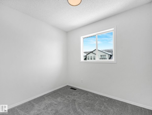 This room features plush grey carpet, neutral white walls, and a window providing natural light - 14 15128 22 Street, Edmonton, AB - Indoor Photo Showing Other Room