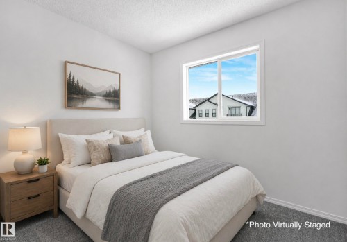 The property features a bedroom with neutral walls, carpeted flooring, and a window providing natural light. Photo Virtually Staged. - 14 15128 22 Street, Edmonton, AB - Indoor Photo Showing Bedroom